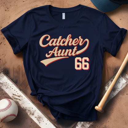 Navy blue t-shirt with 'Catcher Aunt 66' text, baseball, bat, and cap on a wooden surface